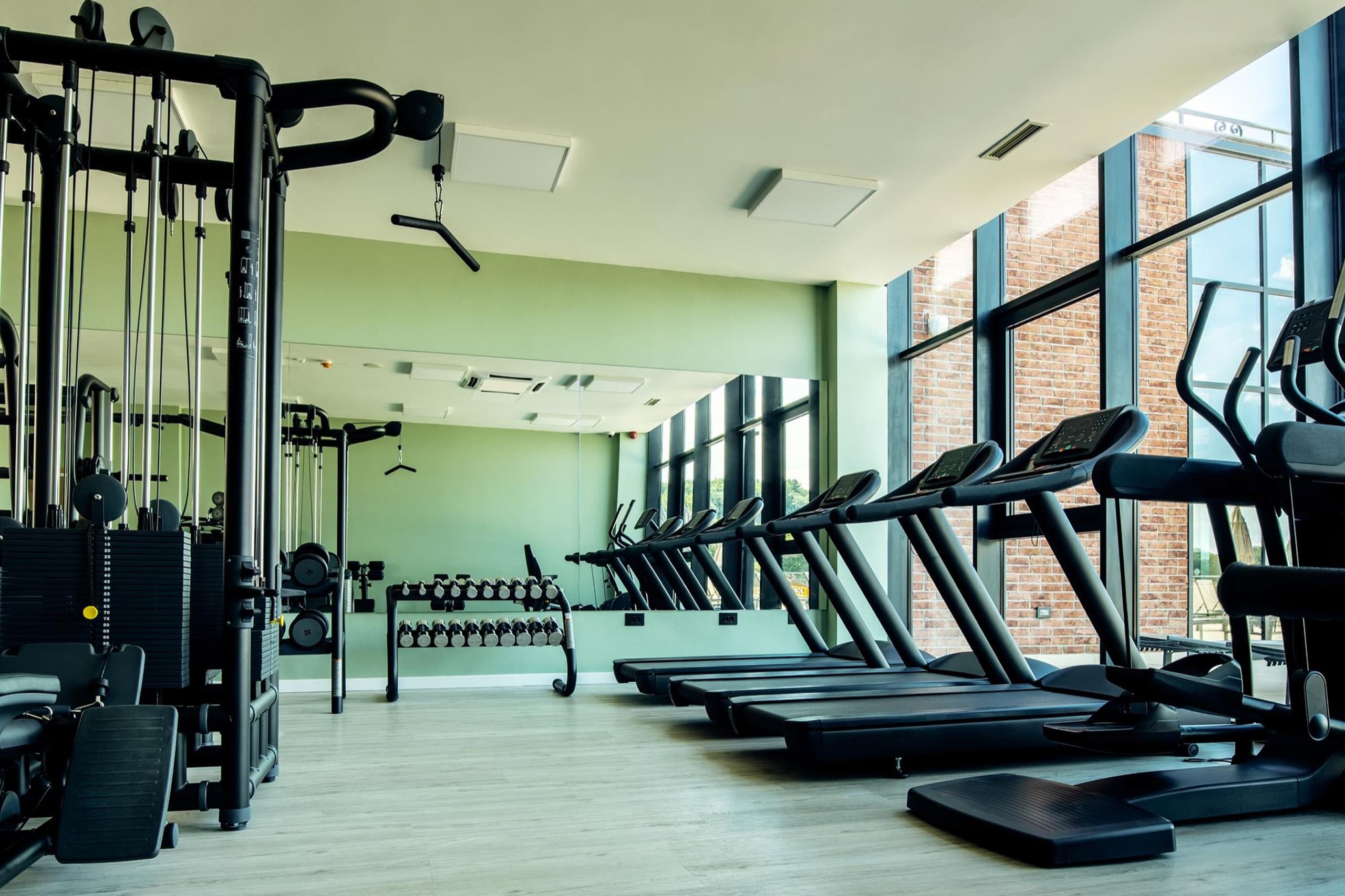 Modern commercial fitness center filled with natural light and rows of equipment
